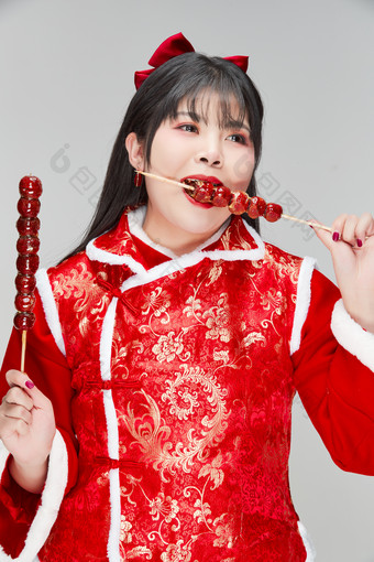 身穿喜庆服饰手拿糖葫芦吃的可爱亚洲少女