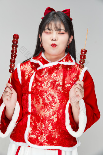 身穿<strong>喜庆</strong>服饰手拿糖葫芦吃的可爱亚洲少女