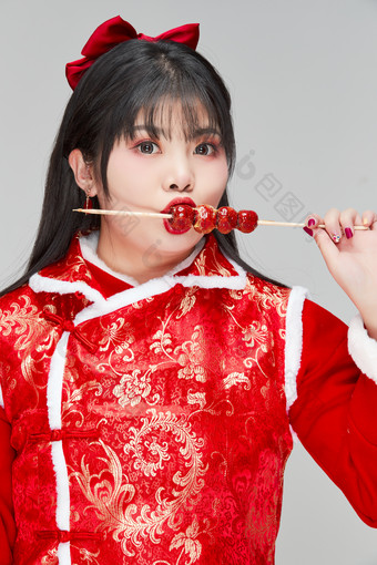 身穿喜庆服饰手拿糖葫芦吃的可爱亚洲少女