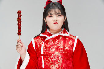 身穿<strong>喜庆</strong>服饰手拿糖葫芦吃的可爱亚洲少女