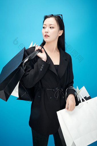青蓝色背景下手提购物袋的亚洲时尚少女