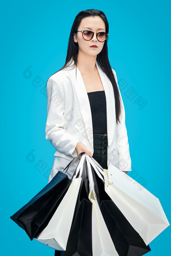 青蓝色背景下手提购物袋的亚洲时尚少女