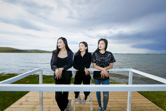 悠闲的站在美丽湖岸码头的亚洲年轻女性人像