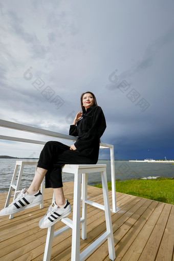 悠闲的坐在美丽湖岸码头的长发少女