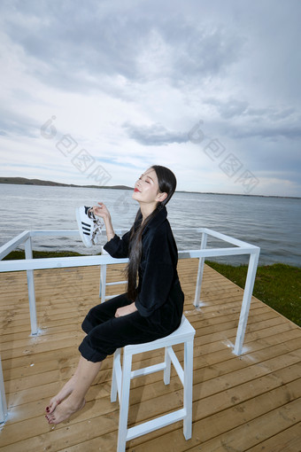 悠闲的坐在美丽湖岸码头的长发少女