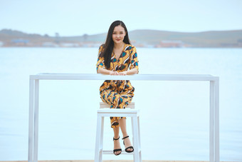 悠闲的坐在美丽湖岸码头的亚洲年轻女性人像