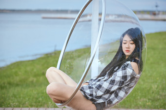 草原湖畔坐在透明秋千里的亚洲年轻女性人像