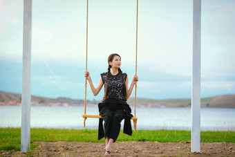 草原湖畔夕阳下荡秋千的亚洲少女