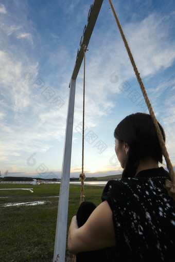 草原湖畔夕阳下荡秋千的亚洲少女