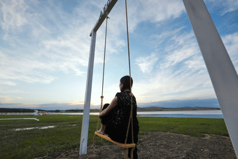 草原<strong>湖畔</strong>夕阳下荡秋千的亚洲少女