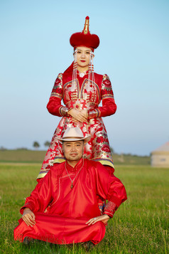 草原上蒙古包前穿蒙古族传统服饰的年轻夫妻