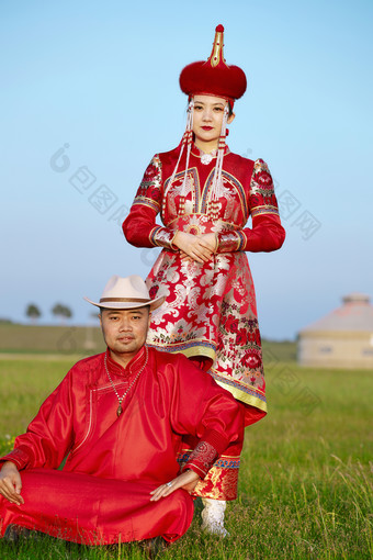 草原上蒙古包前穿蒙古族传统服饰的年轻夫妻