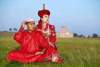 草原上蒙古包前穿蒙古族传统服饰的年轻夫妻