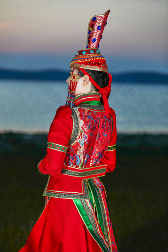 晚霞的草原湖畔穿蒙古族传统服饰的年轻女性