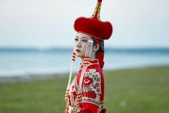 晚霞的草原<strong>湖畔</strong>穿蒙古族传统服饰的年轻女性