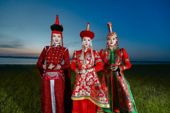 晚霞的草原湖畔穿蒙古族传统<strong>服饰</strong>的年轻女性