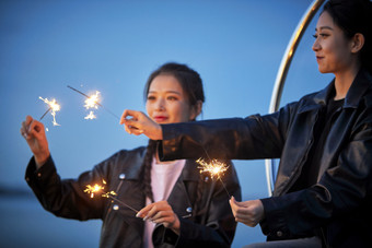 傍晚湖畔透明秋千上燃<strong>放</strong>仙女棒的可爱少女