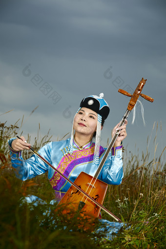 草原上穿蒙古族服饰拉马头琴的蒙族女乐手