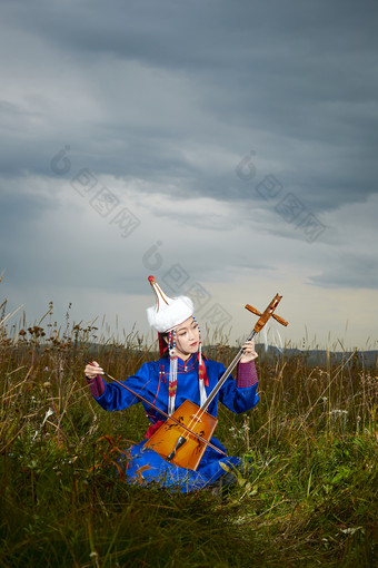 草原上穿蒙古族服饰拉马头琴的蒙族女乐手