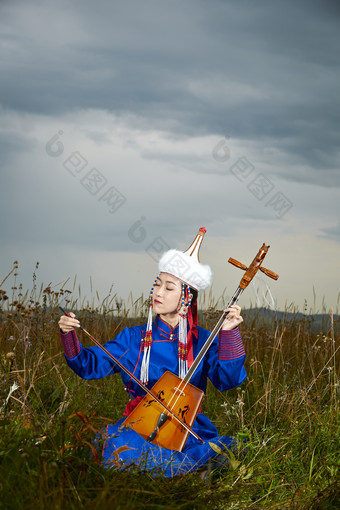 草原上穿蒙古族服饰拉马头琴的蒙族女乐手