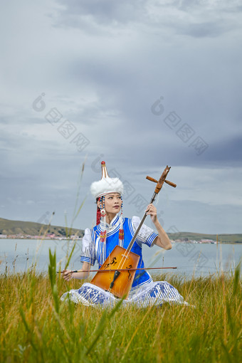 草原上穿蒙古族服饰拉马头琴的蒙族女乐手