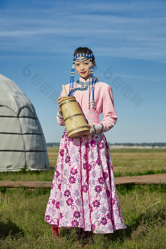 蒙古包前穿<strong>蒙古族</strong>饰怀抱奶茶桶的蒙族少女