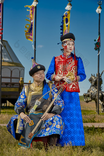 草原上蒙古包前穿蒙古族传统服饰的年轻夫妻