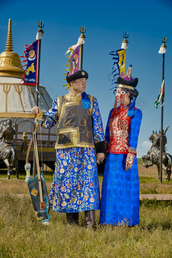 草原上蒙古包前穿蒙古族传统服饰的年轻夫妻图片