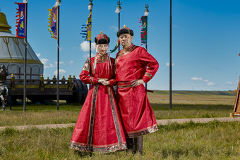 草原上蒙古包前穿蒙古族传统服饰的年轻夫妻