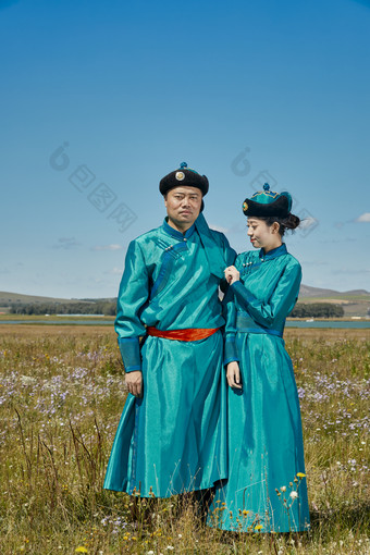 草原上蒙古包前穿蒙古族传统服饰的年轻夫妻图片