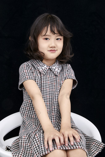 黑色背景里坐在凳子上的可爱的亚洲小女孩儿童