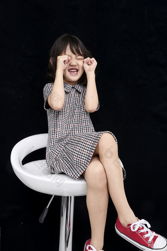 黑色背景里坐在凳子上的可爱的亚洲小女孩儿童