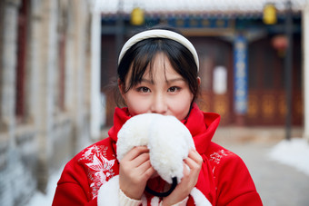 雪后在老城古巷穿着喜庆服饰的亚洲少女