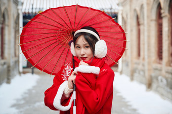 雪后在老城古巷穿着喜庆服饰的亚洲少女