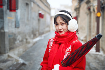 雪后在老城古巷穿着喜庆服饰的亚洲少女