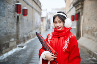 雪后在老城古巷穿着喜庆服饰的亚洲少女