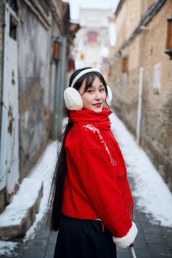 雪后在老城古巷穿着喜庆服饰的亚洲少女