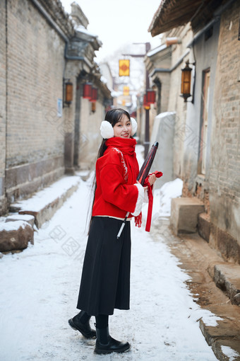 雪后在老城古巷穿着喜庆服饰的亚洲少女