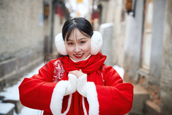 雪后在老城古巷穿着喜庆服饰的亚洲少女