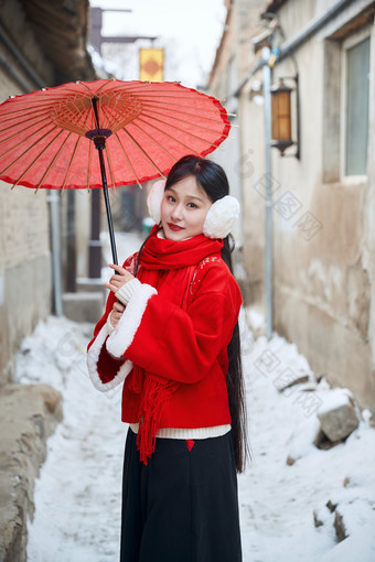 雪后在老城古巷穿着喜庆服饰的亚洲少女