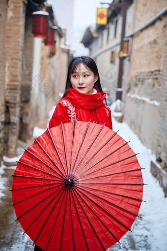 雪后在老城古巷穿着喜庆服饰的亚洲少女