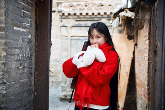 雪后在老城古巷穿着喜庆服饰的亚洲少女