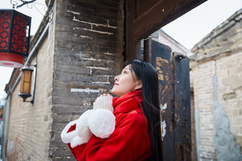 雪后在老城古巷穿着喜庆服饰的亚洲少女