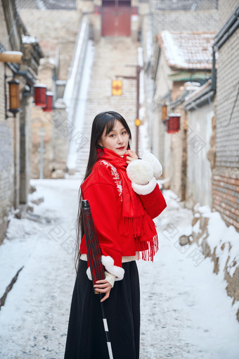 雪后在老城古巷穿着喜庆服饰的亚洲少女