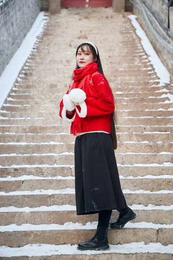 雪后在老城古巷穿着喜庆服饰的亚洲少女