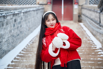 雪后在老城古巷穿着喜庆服饰的亚洲少女