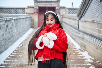 雪后在老城古巷穿着喜庆服饰的亚洲少女