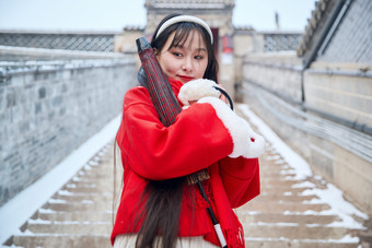 雪后在老城古巷穿着喜庆服饰的亚洲少女