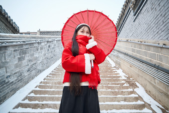 雪后在老城古巷穿着喜庆服饰的亚洲少女