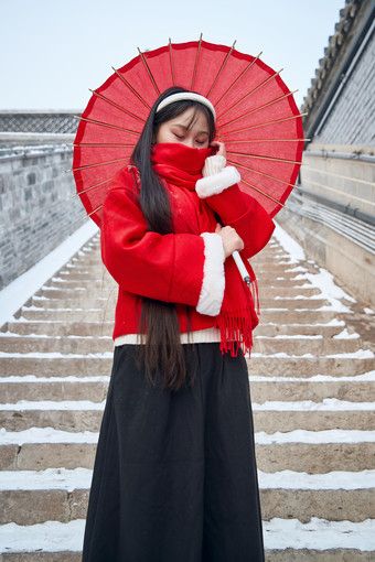 雪后在老城古巷穿着喜庆服饰的亚洲少女